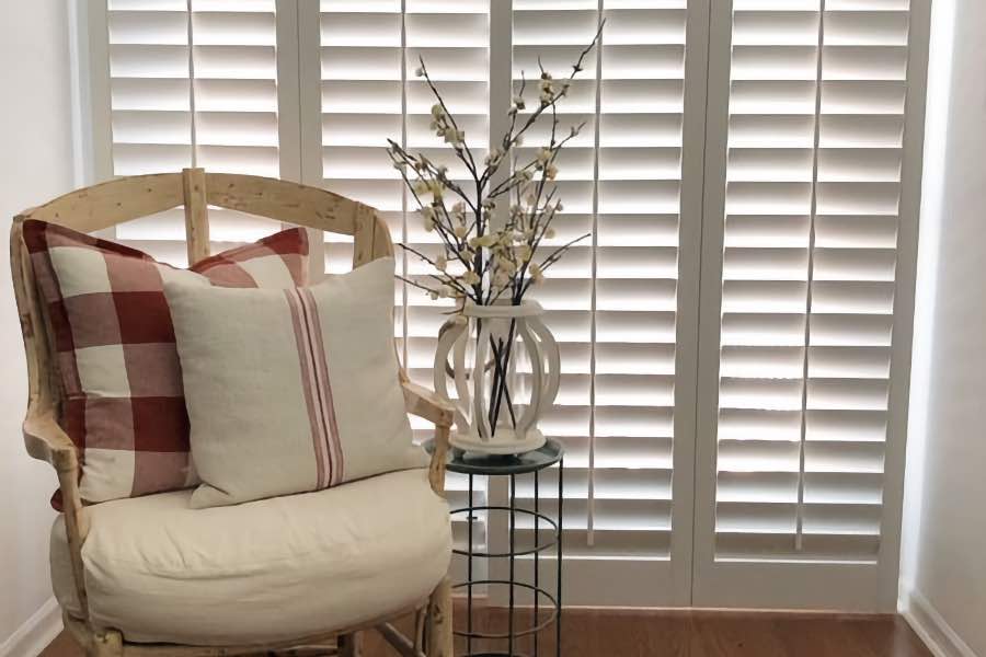 White plantation shutter with adjustable louvers covering a sliding door