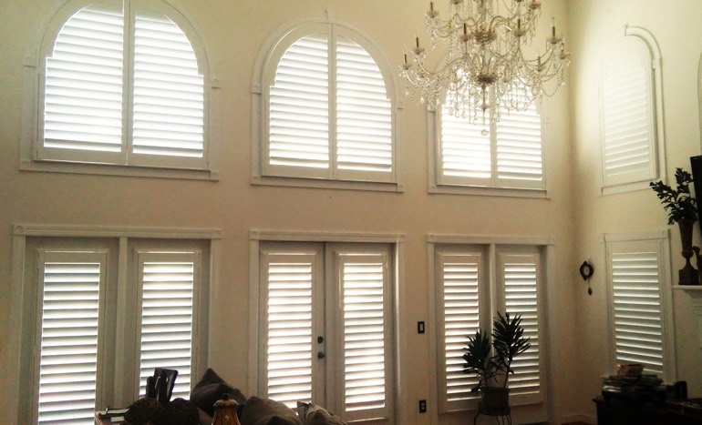 Family room in two-story Charlotte house with plantation shutters on high windows.