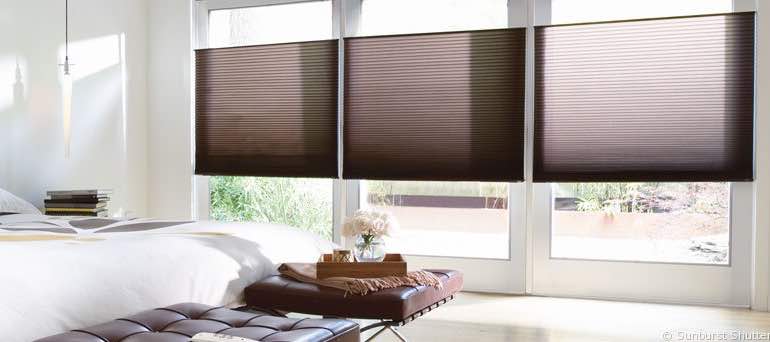 Modern Charlotte bedroom with tall windows and brown honeycomb shades.