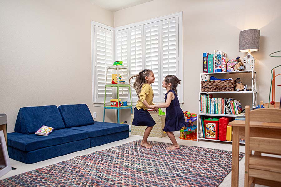 Two girls playing in a toy room with Polywood shutters on the windows