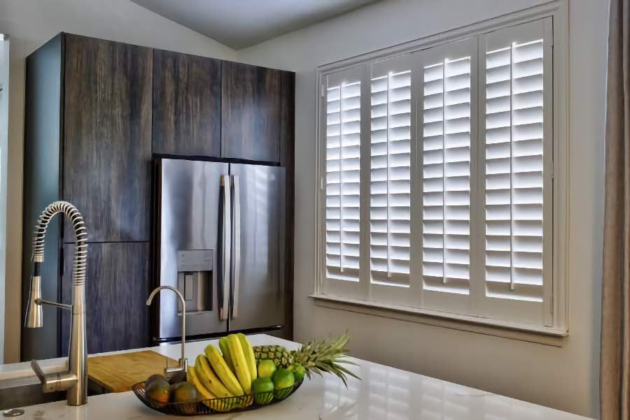 Homeowners use indoor window shutters in Charlotte when they want attractive and functional window treatments. Polywood shutters on a large kitchen window