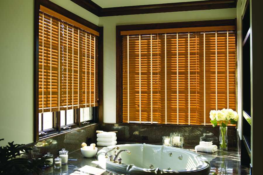 Premium quality blinds are always a stylish accent in your Charlotte home. Brown wood blinds on large windows in a green bathroom