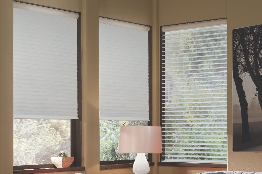 Opaque motorized window shades in Charlotte keep hot UV rays out of your home. Gray motorized sheer shades on corner windows next to gray furniture