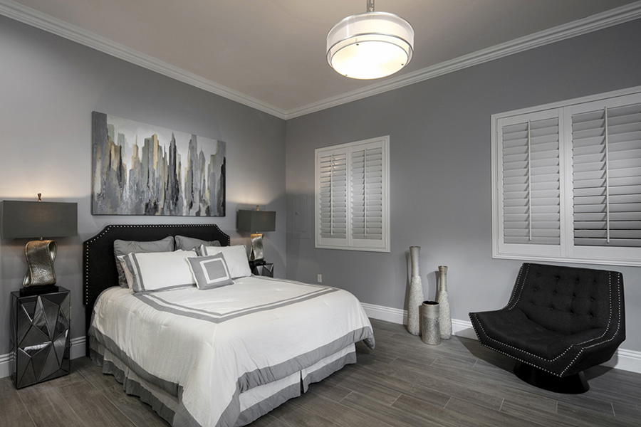 Interior shutters keep out all sunlight when you want a cozy, dark room for sleeping. White Polywood shutters in a dim bedroom