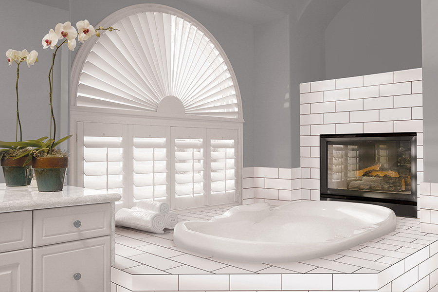 Explore our selection of window treatments for builders in Charlotte to find the perfect ones for your next construction project. White Polywood shutters on an arched bathroom window