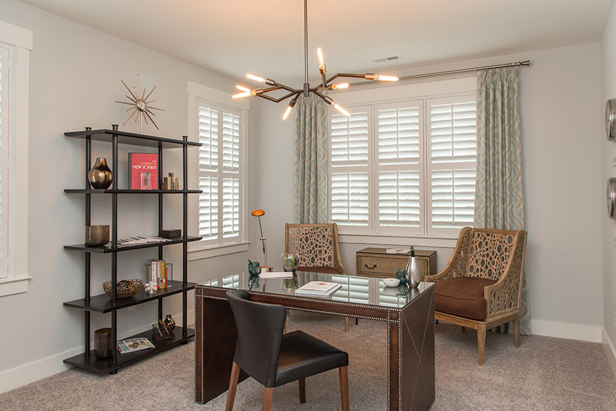 Colorful curtains can add a bit of flair with white Polywood shutters in Charlotte. Sage green patterned curtains on white polywood shutters in an office.