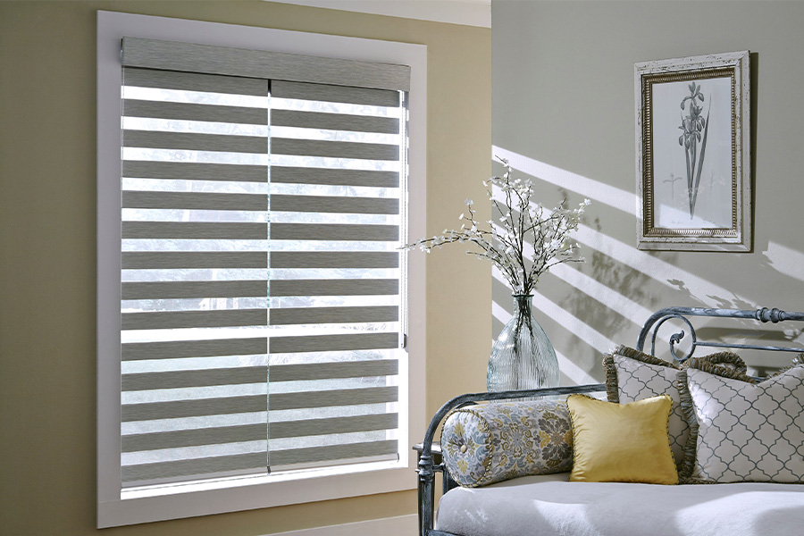 Find Practical and stylish window blinds for Charlotte homes at Sunburst. Gray blinds on a large window next to a couch.