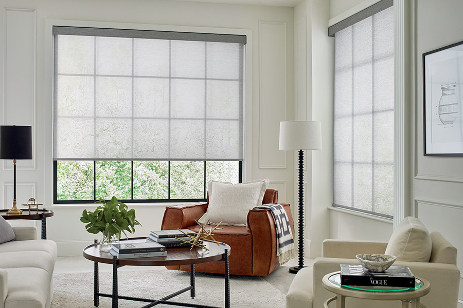 Sheer shades add contrast and style to your living room. Light gray sheer shades on two large tall windows with a beige and tan styled living room.