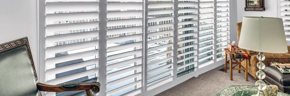 White plantation shutters letting light through a sliding glass door