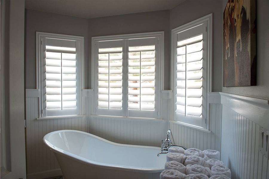 Water-resistant,durable, and beautiful Polywood Shutters  White Polywood shutters above a clawfoot white tub